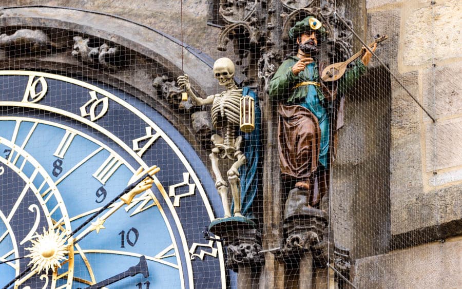布拉格天文鐘盤旁的骷髏代表「死亡」，會拉動鈴鐺；旁邊的土耳其人則象徵「慾望」。