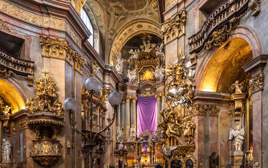 巴洛克教堂內部祭壇裝飾，大理石柱、雕像與宗教畫作層層堆疊，空間充滿戲劇感。