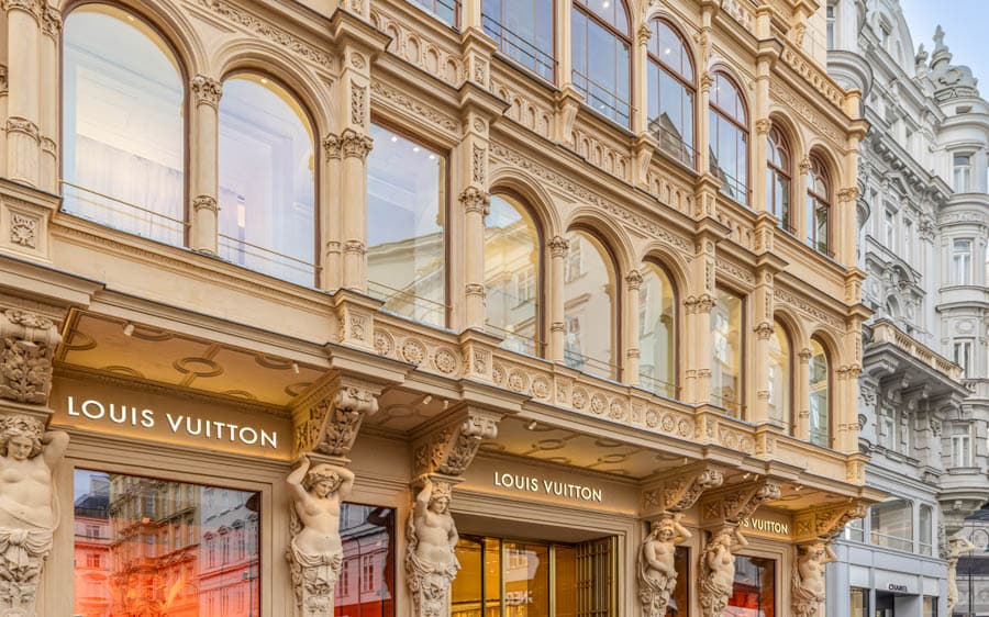 維也納市中心精品街建築外觀，華麗歷史立面與拱窗細節，街頭可見精品店門面。