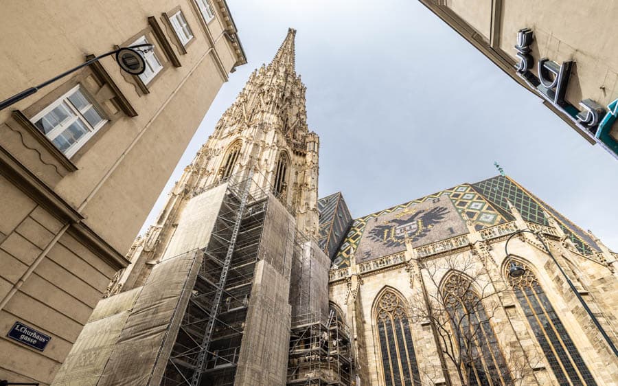 維也納聖史蒂芬大教堂外觀，哥德式尖塔高聳入天際，街道兩側建築形成仰角視野。