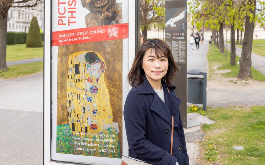 女性站在維也納美景宮名畫海報前