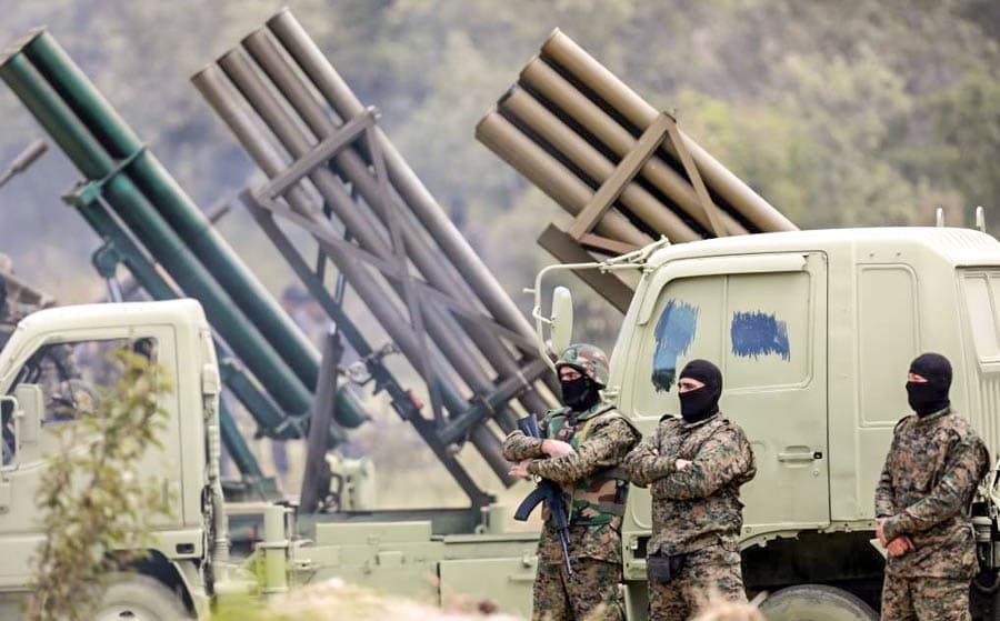 黎巴嫩真主黨武裝人員站在火箭發射車前方，展示火箭部隊與軍事裝備